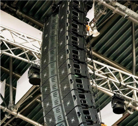 Large vertical array of black speakers suspended from ceiling metal framework for sound reinforcement